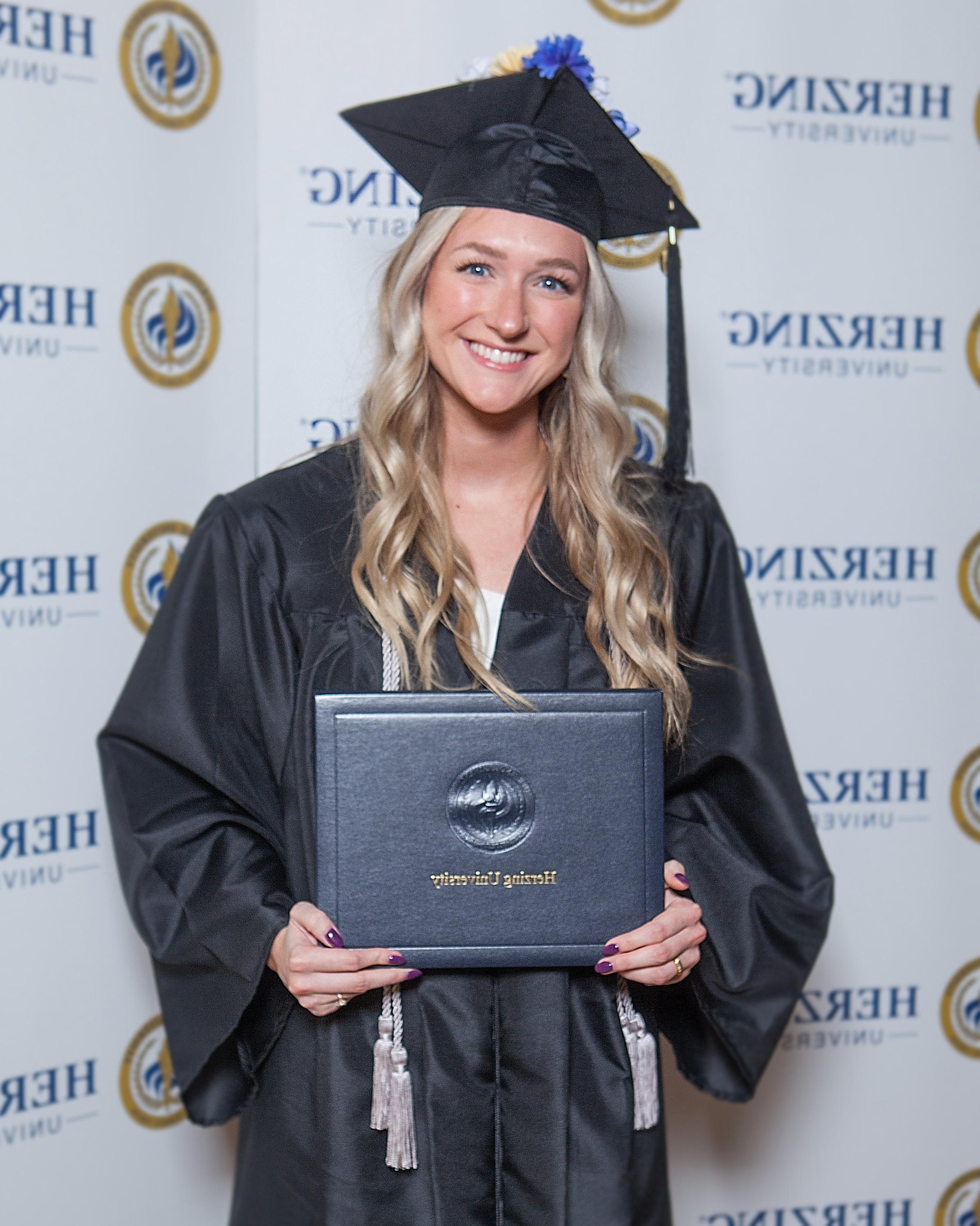 Herzing graduate smiling and holding degree